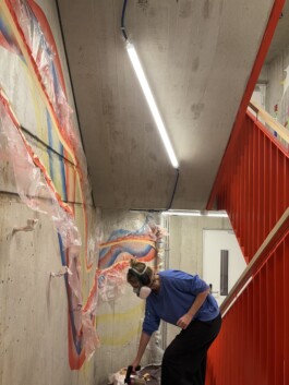 Abstrakte Wandarbeit „Sektor 6“ von Charlotte Wielage im sechsten Stock der Villa Viva, 2023; farbige Linienstrukturen auf Betonwand, 530 × 254 cm