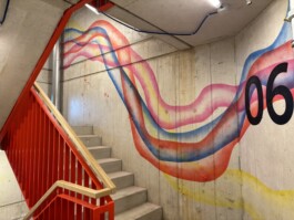 Abstrakte Wandarbeit „Sektor 6“ von Charlotte Wielage im sechsten Stock der Villa Viva, 2023; farbige Linienstrukturen auf Betonwand, 530 × 254 cm