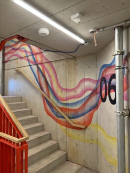 Abstrakte Wandarbeit „Sektor 6“ von Charlotte Wielage im sechsten Stock der Villa Viva, 2023; farbige Linienstrukturen auf Betonwand, 530 × 254 cm