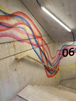 Abstrakte Wandarbeit „Sektor 6“ von Charlotte Wielage im sechsten Stock der Villa Viva, 2023; farbige Linienstrukturen auf Betonwand, 530 × 254 cm